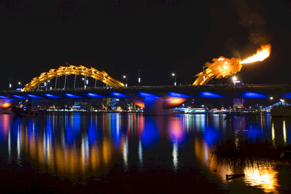 The Dragon Bridge in Da Nang, Vietnam, lights up the night as its golden dragon breathes fire, creating a mesmerizing spectacle over the Han River